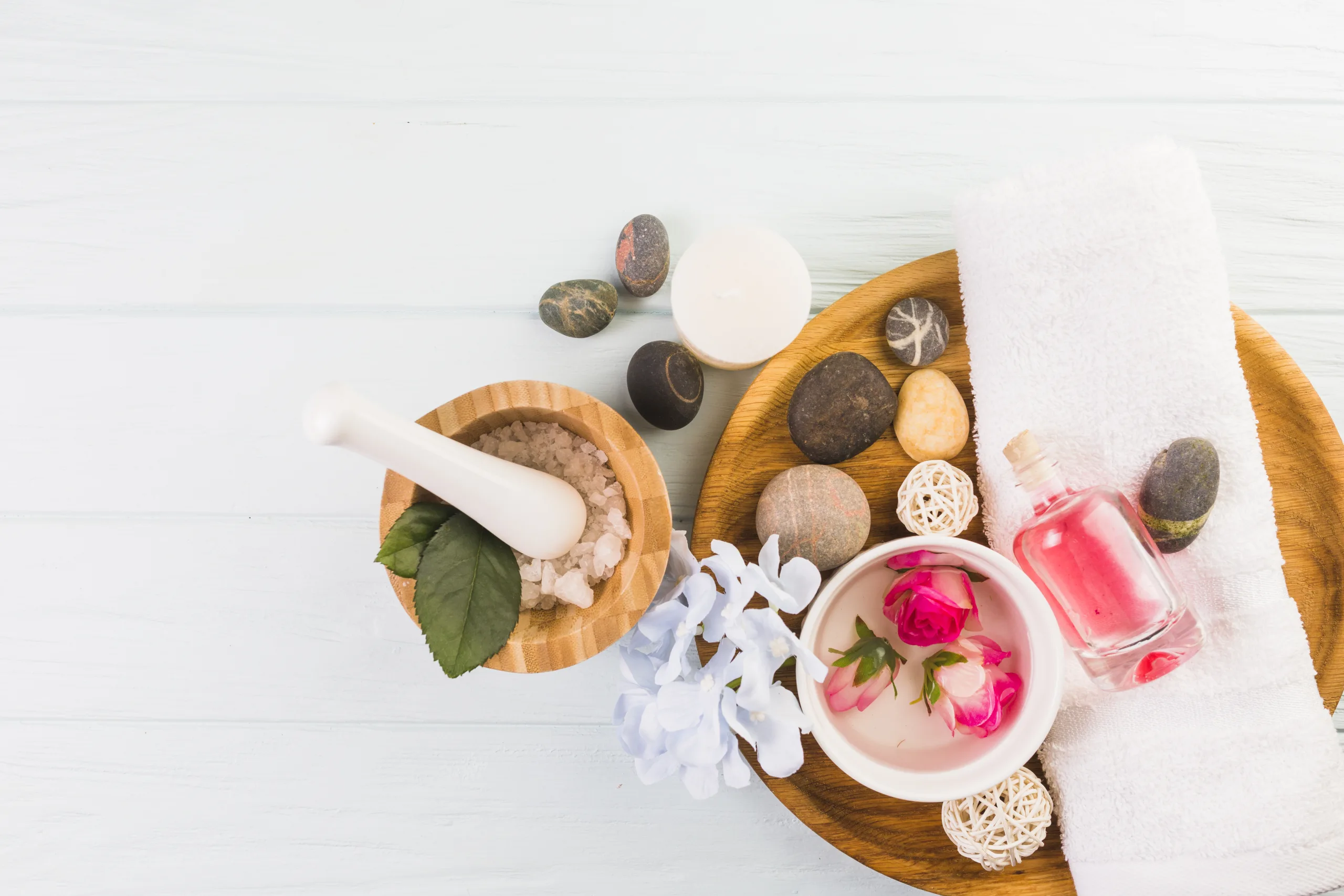 elevated-view-spa-stones-salt-towel-flowers-oil-white-background